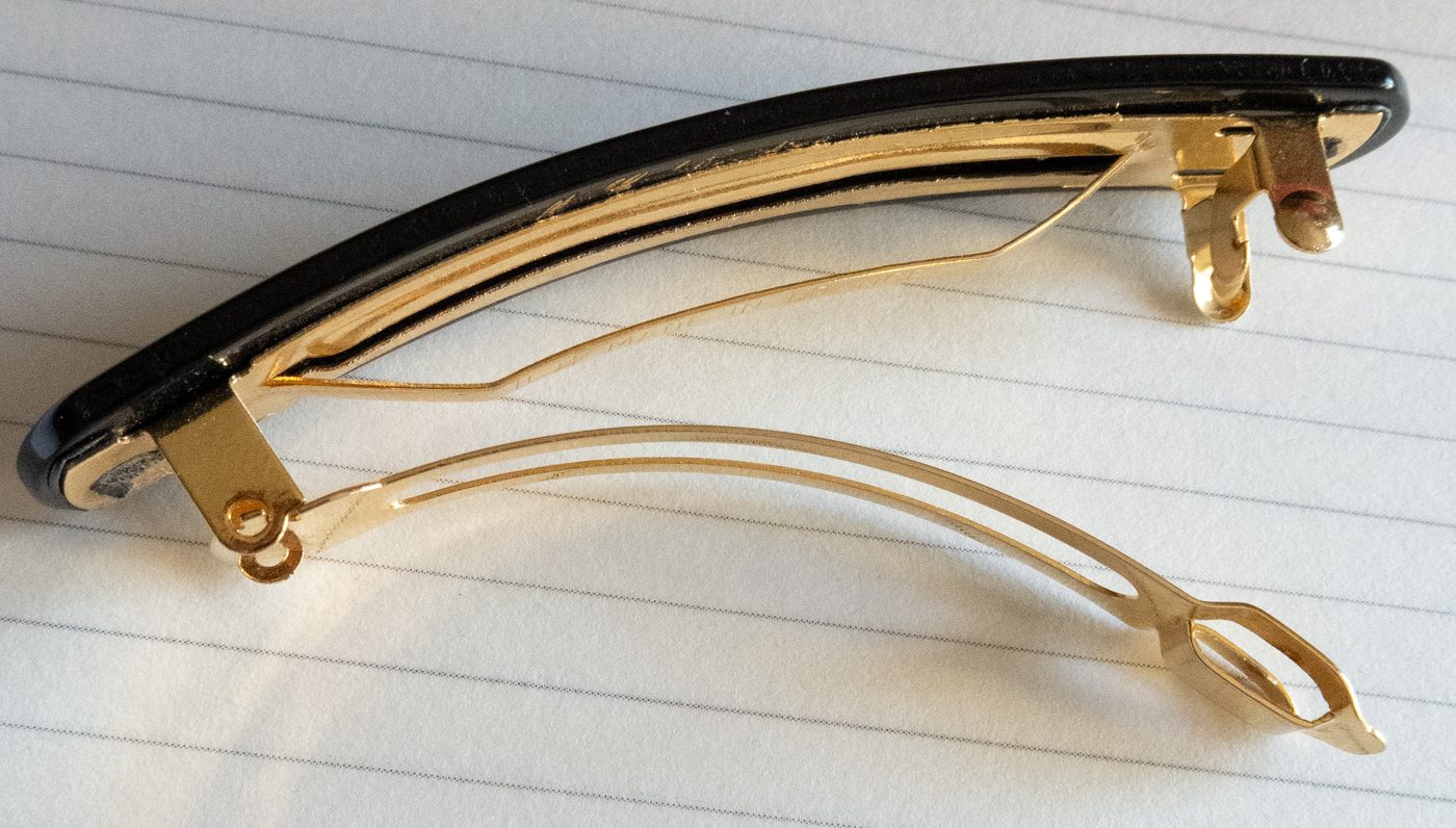 Monture matic ouverte au dos d'une barrette noire : lame ressort et tige articulée